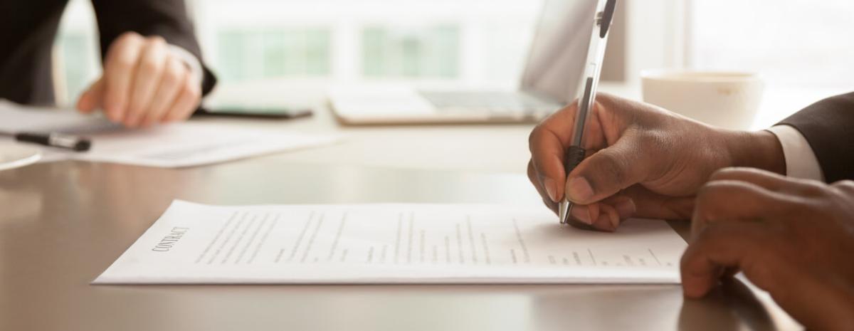 Horizontal close up photo african businessman sitting at desk holds pen signing contract paper, lease mortgage, lease agreement concept