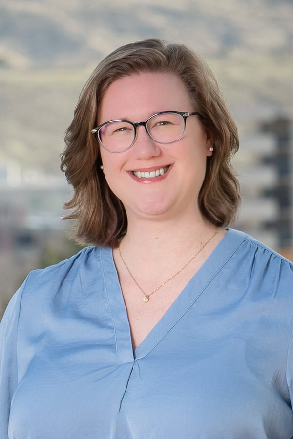 Professional portrait of Laura McCauley in blue scrubs with glasses.