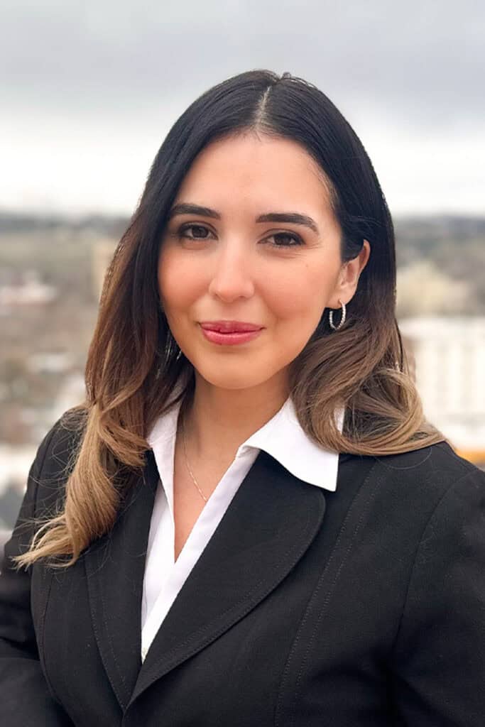 Professional woman in business attire outdoors with cityscape background.