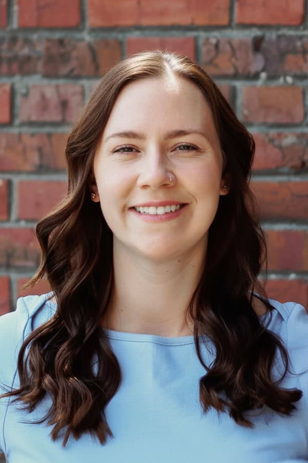 Portrait of Sage Caldwell smiling against a brick wall background.