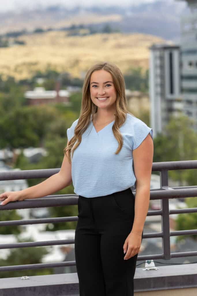 Katie Freshwater smiling outdoors in Boise with cityscape background.
